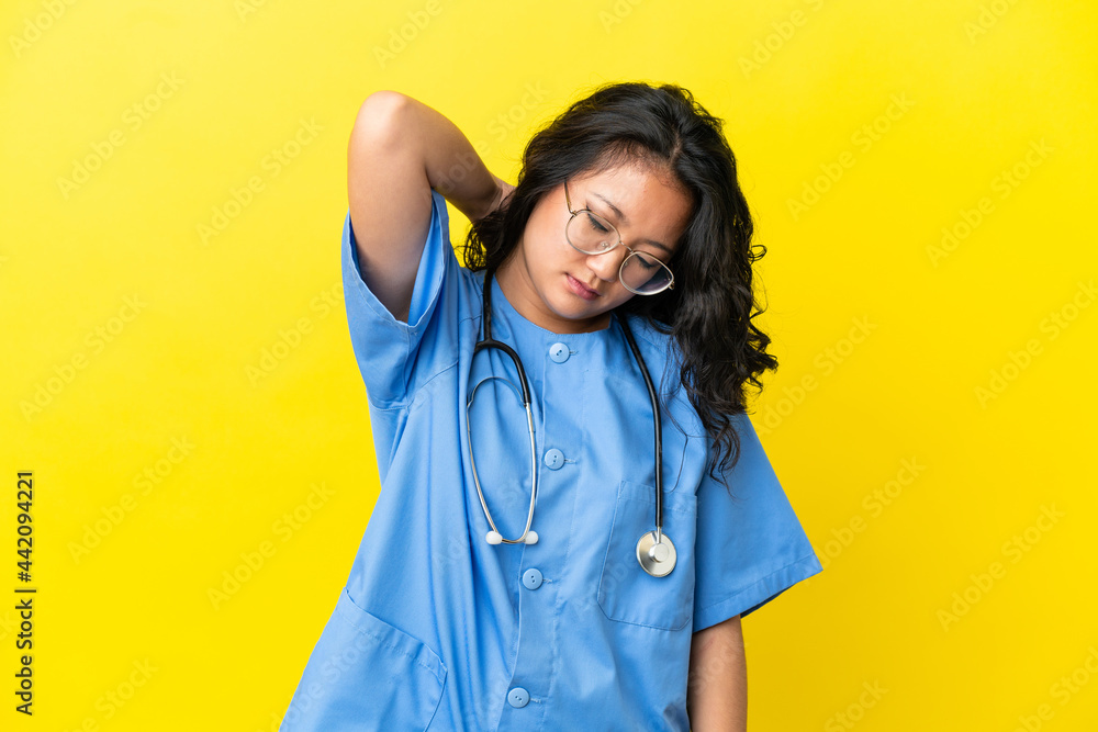 Young surgeon doctor asian woman isolated on yellow background with neckache Young surgeon doctor asian woman isolated on yellow background with neckache