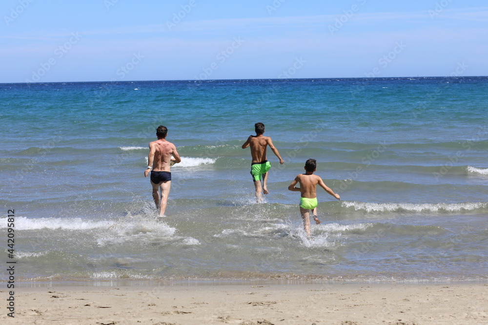 Tata i synowie podczas wygłupów na plaży. Dad and sons on the beach. - obrazy, fototapety, plakaty 