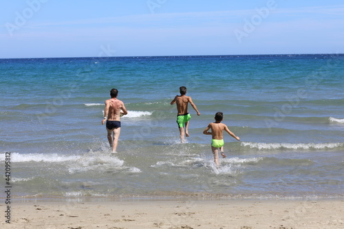 Fototapeta Naklejka Na Ścianę i Meble -  Tata i synowie podczas wygłupów na plaży. Dad and sons on the beach.