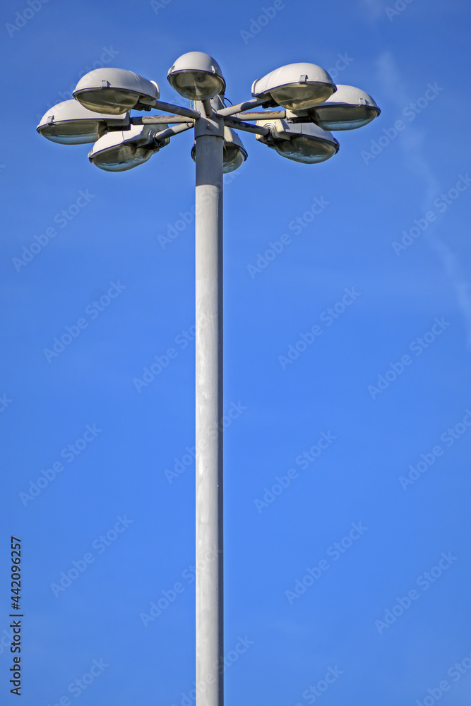 The upper part of the mast of street lighting on the background of the blue sky The upper part of the mast of street lighting on the background of the blue sky