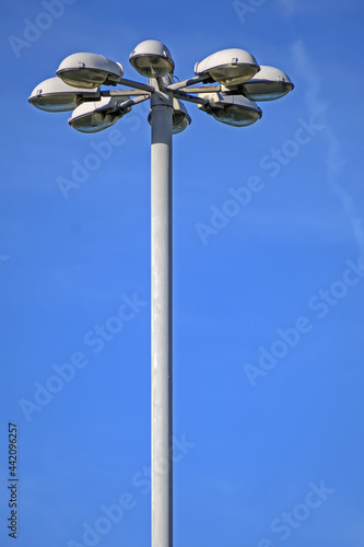 The upper part of the mast of street lighting on the background of the blue sky