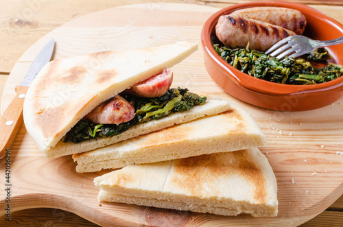 Torta al testo, flatbread with spinach and grilled sausage - traditional umbrian Italy streetfood. photo