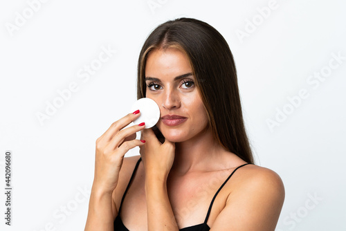 Young Uruguayan woman isolated on white background with cotton pad for removing makeup from her face