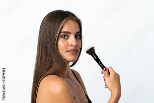Young Uruguayan woman isolated on white background holding makeup brush