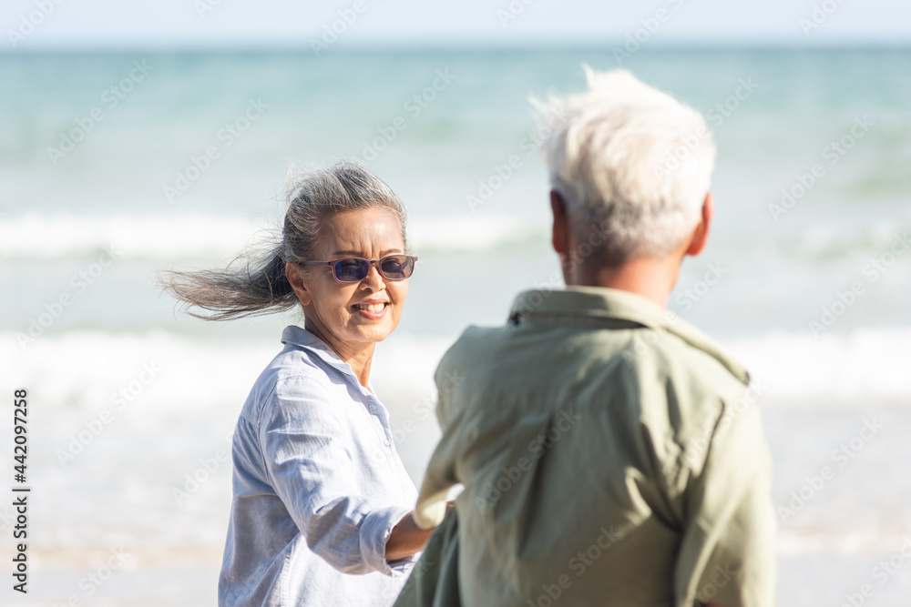 Happy Asian senior man and woman couple holding hands walking to the beach sunny with bright blue sky, Romantic elderly enjoy Travel summer vacation, plan life insurance at retirement couple concept Happy Asian senior man and woman couple holding hands walking to the beach sunny with bright blue sky, Romantic elderly enjoy Travel summer vacation, plan life insurance at retirement couple concept