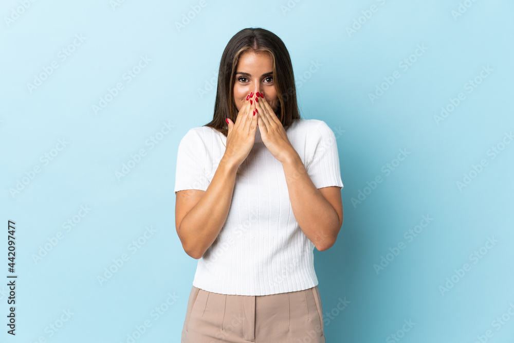 Young Uruguayan woman isolated on blue background happy and smiling covering mouth with hands Young Uruguayan woman isolated on blue background happy and smiling covering mouth with hands