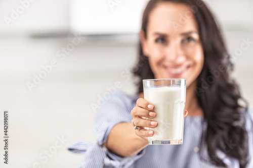 Glass of milk held by a woman towards a camera