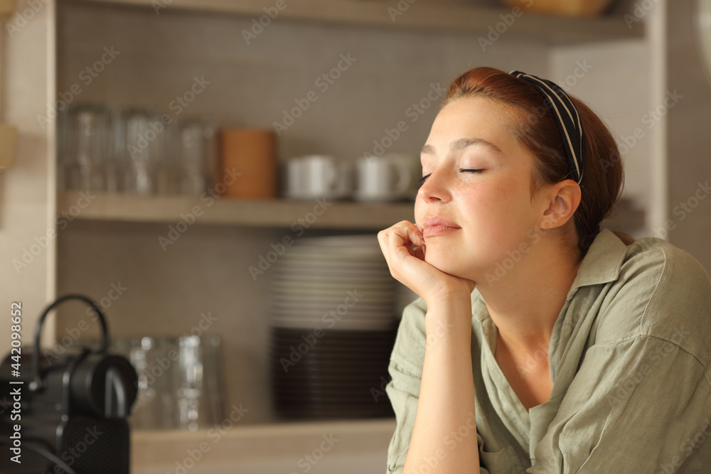 Relaxed woman resting with closed eyes in the kitchen Relaxed woman resting with closed eyes in the kitchen