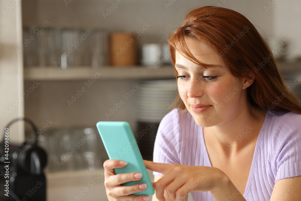 Woman using smart phone in the kitchen Woman using smart phone in the kitchen
