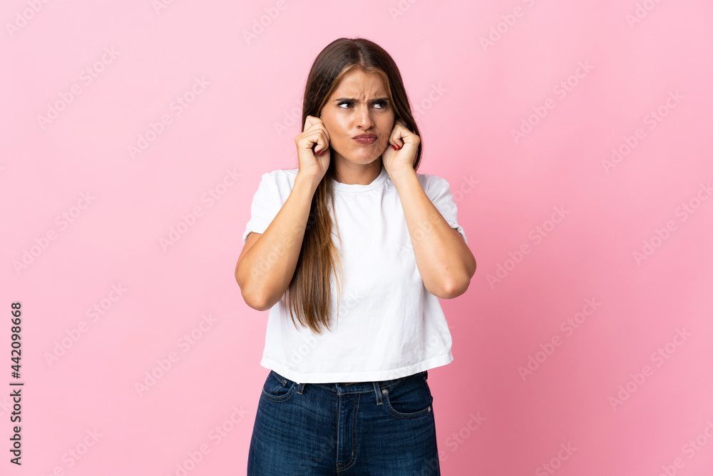 Young Uruguayan woman isolated on pink background frustrated and covering ears Young Uruguayan woman isolated on pink background frustrated and covering ears