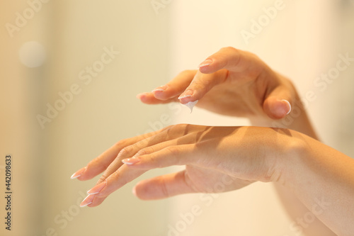 Woman hands applying moisturizer cream in the bathroom
