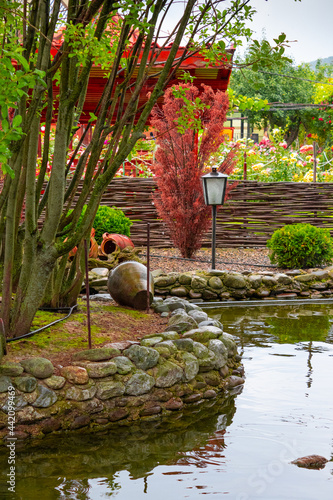 Landscape design in home garden, beautiful landscaping with small pond and stones. Landscaped place with stones and water. 
