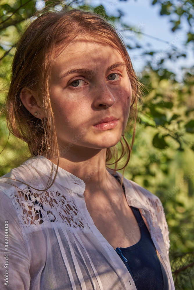 A teenage girl in a white shirt in a forest, illuminated by the sun's rays. A teenage girl in a white shirt in a forest, illuminated by the sun's rays.