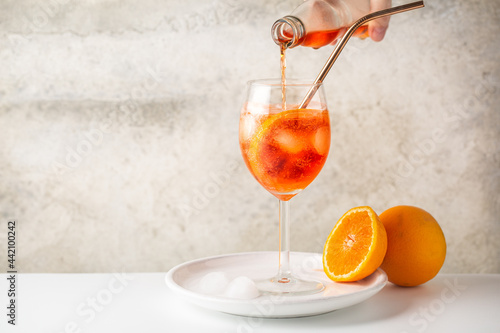 Preparing aperol spritz cocktail with slice of orange. Flowing drink. Copy space.