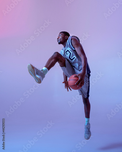 Basketball player moving with ball in studio