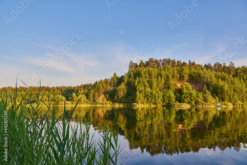  Hills covered with forest are reflected in the surface of the lake. © FO_DE