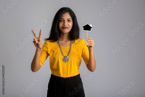 A young girl or businesswoman holding a little cutout board and posing on a gray background.