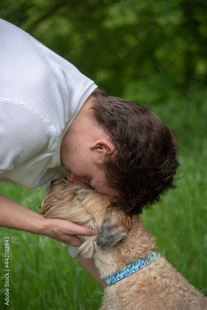A teenage boy hugs his furry dog on a walk. A teenage boy hugs his furry dog on a walk.
