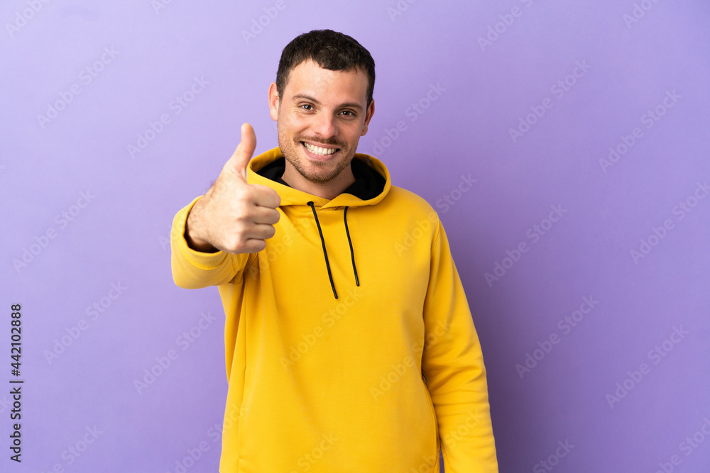 Brazilian man over isolated purple background with thumbs up because something good has happened Brazilian man over isolated purple background with thumbs up because something good has happened