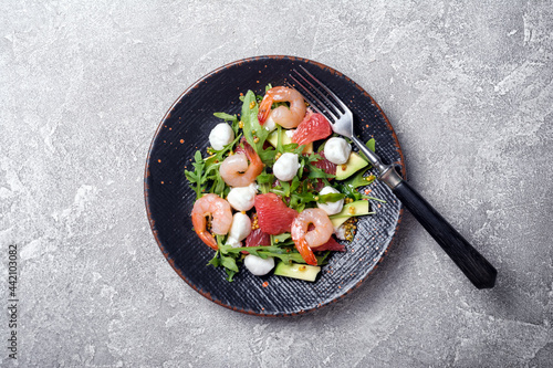 Healthy salad with fresh arugula, mozzarella cheese, tasty shrimps, grapefruit and avocado