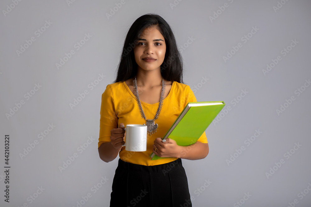 Pretty young girl with a cup of tea or coffee posing on grey background Pretty young girl with a cup of tea or coffee posing on grey background