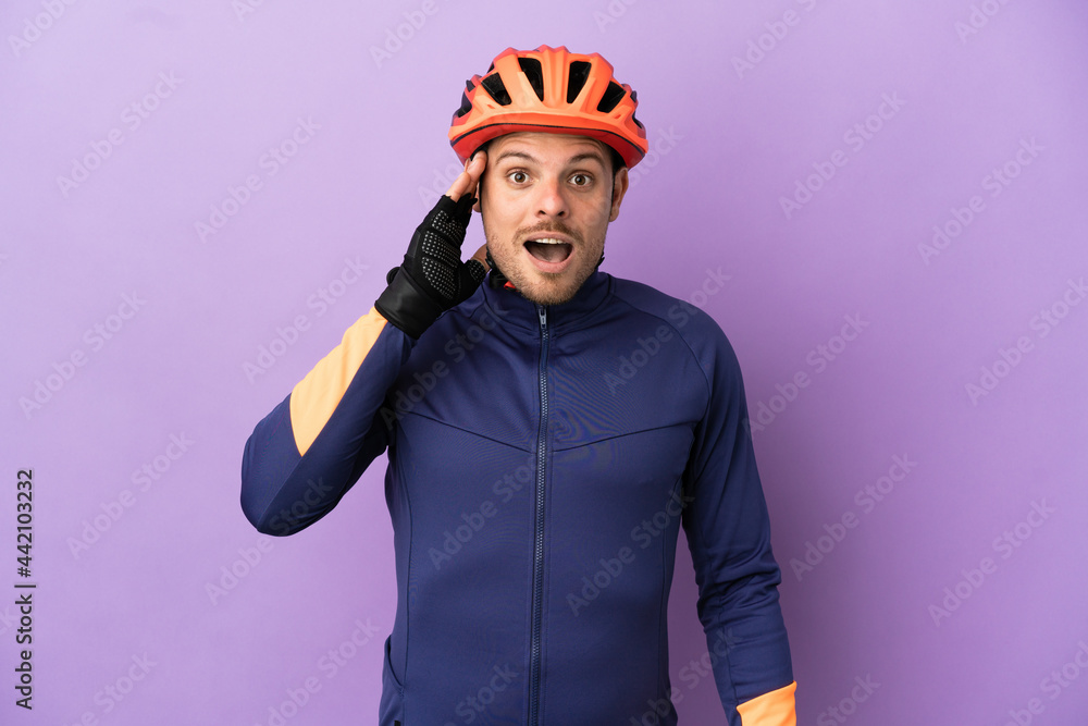 Fototapeta premium Young Brazilian cyclist man isolated on purple background with surprise and shocked facial expression