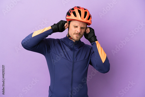 Young Brazilian cyclist man isolated on purple background frustrated and covering ears © luismolinero
