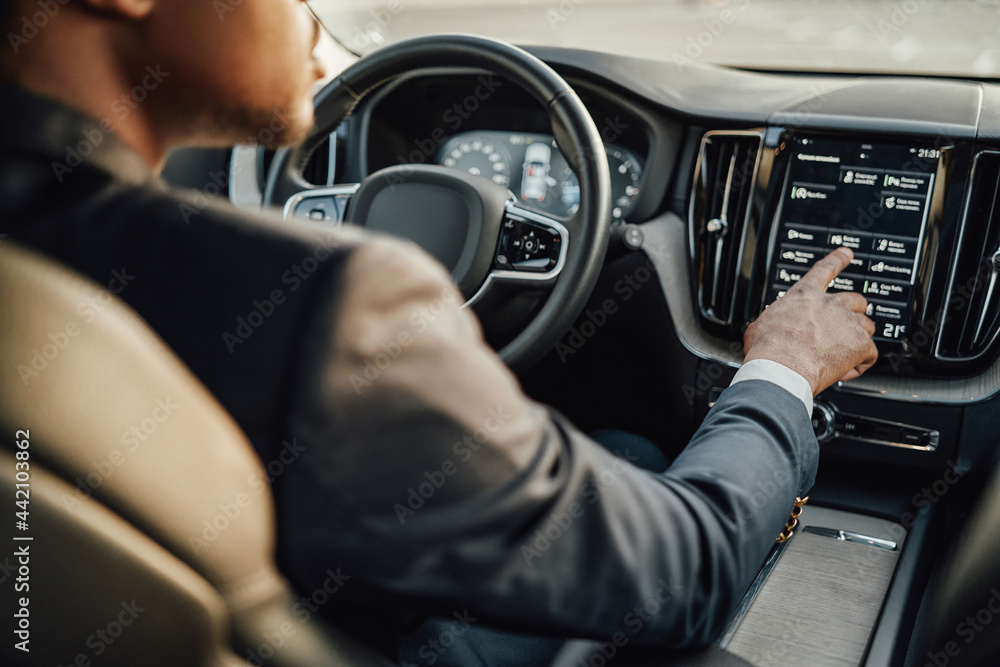 Black businessman inside car using car panel Black businessman inside car using car panel