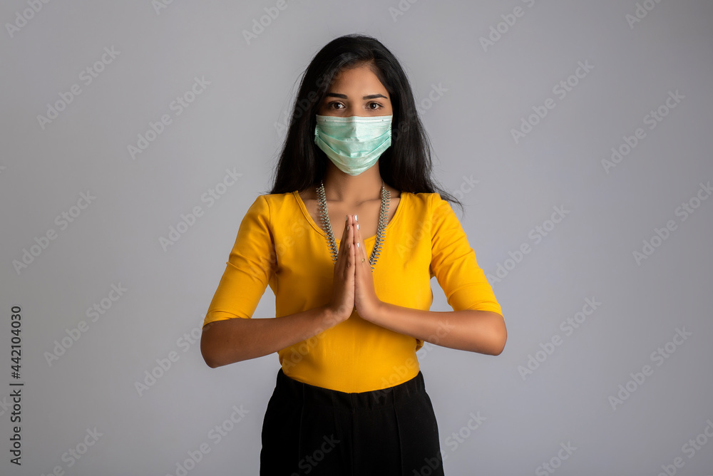 Portrait of a girl wearing a medical mask doing greeting with Namaste gesture. Portrait of a girl wearing a medical mask doing greeting with Namaste gesture.