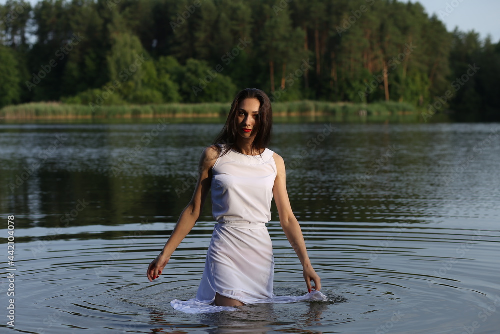 Brunette woman in white dress standing in water Brunette woman in white dress standing in water