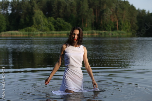 Fototapeta Naklejka Na Ścianę i Meble -  Brunette woman in white dress standing in water
