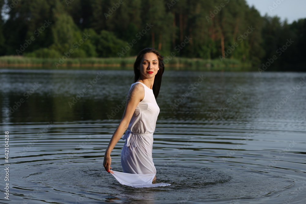 Brunette woman in white dress standing in water Brunette woman in white dress standing in water