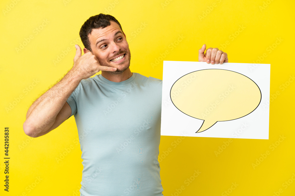 Brazilian man over isolated purple background holding a placard with speech bubble icon and doing phone gesture Brazilian man over isolated purple background holding a placard with speech bubble icon and doing phone gesture