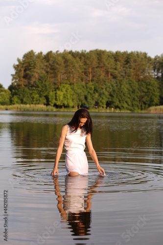 Fototapeta Naklejka Na Ścianę i Meble -  Beautiful brunette woman in white dress in the lake