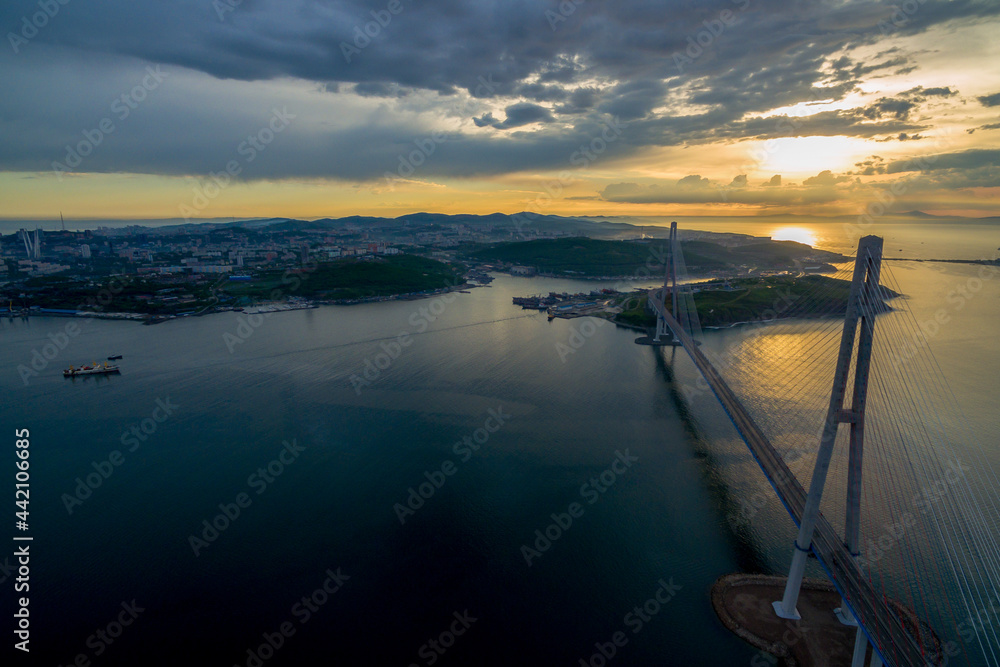 View from above. Russian bridge across the Eastern Bosphorus Strait against the background of a bright dawn. A merchant ship passes under the roadbed of the Russian Bridge.