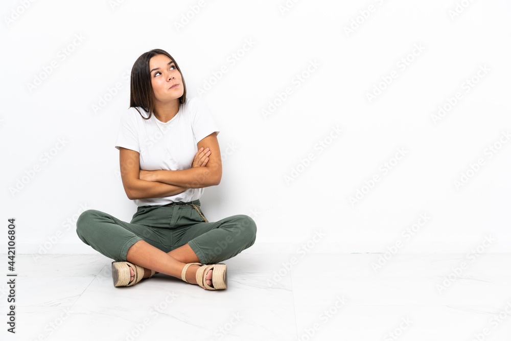 Teenager girl sitting on the floor making doubts gesture while lifting the shoulders Teenager girl sitting on the floor making doubts gesture while lifting the shoulders