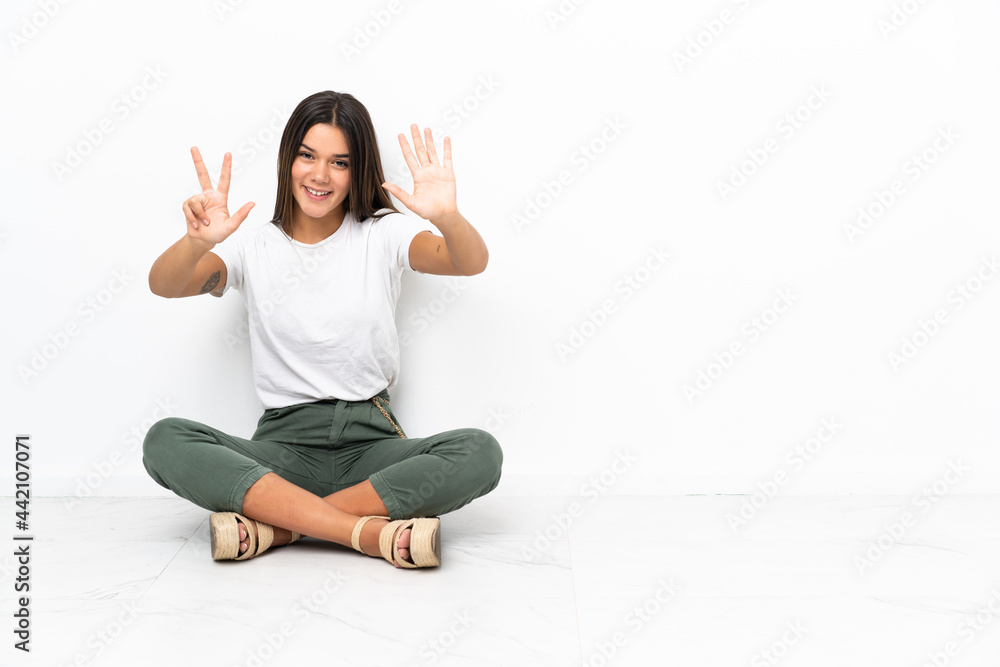 Teenager girl sitting on the floor counting eight with fingers Teenager girl sitting on the floor counting eight with fingers
