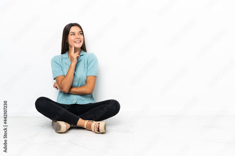Teenager girl sitting on the floor thinking an idea while looking up Teenager girl sitting on the floor thinking an idea while looking up