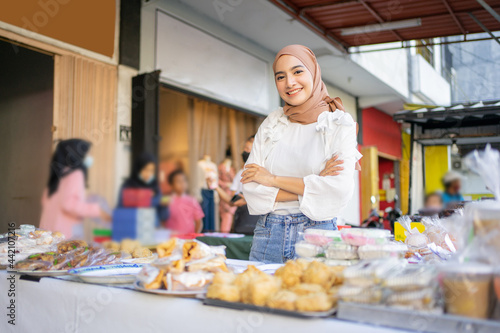 a beautiful girl in a veil with her arms crossed selling various kinds of traditional street food fritters