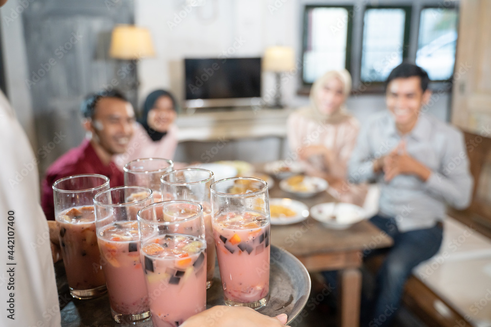 close up of a person carrying a tray serving ice in glasses while having lunch together in the dining room in a traditional house