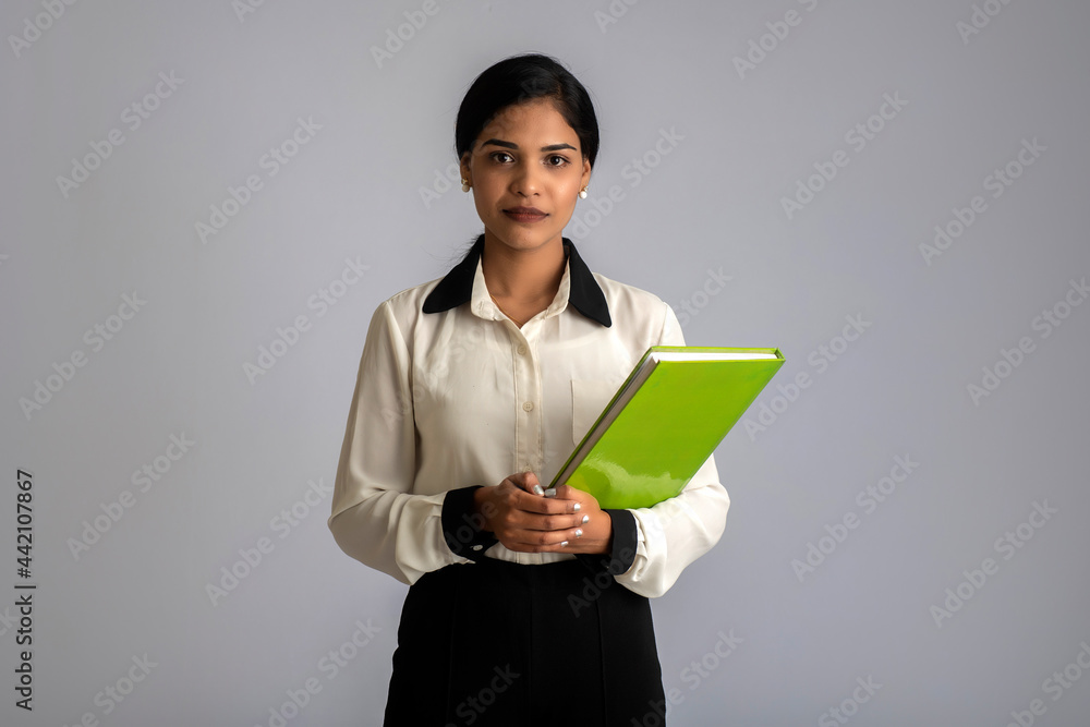 Pretty young girl posing with the book on grey background Pretty young girl posing with the book on grey background