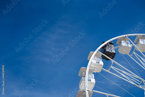 Ferris wheel with white cabins and one black one. Diversity and tokenism concept