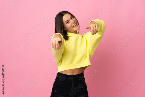 Teenager girl isolated on pink background pointing front with happy expression