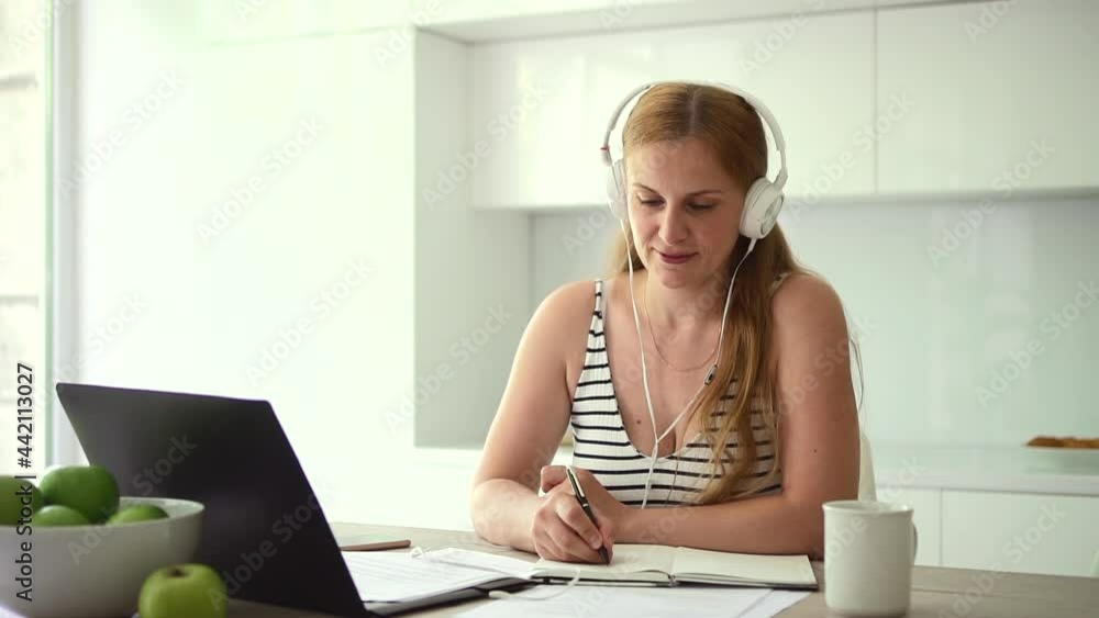 Woman in headphones writes with pen during video lecture Spbd. Woman in headphones writes with pen during video lecture Spbd.