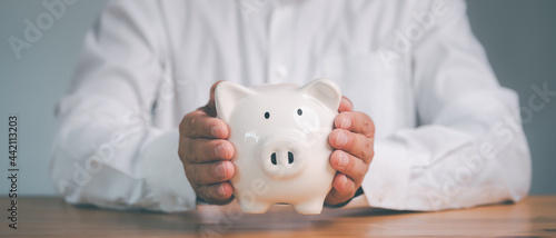 Schilderij op canvas business finance and saving money investment concept, Man hand holding piggy bank on wood table