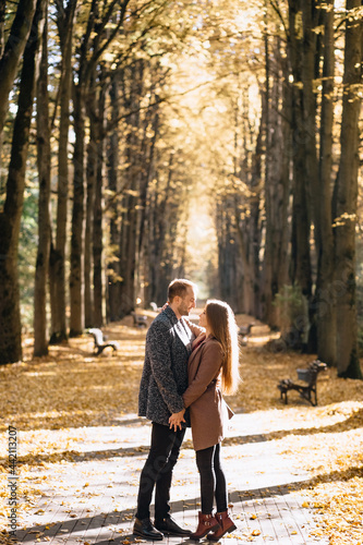 Fototapeta Naklejka Na Ścianę i Meble -  A couple in love embracing in an autumn park at sunset