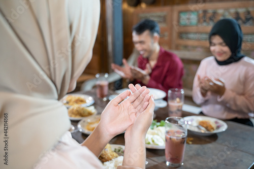 close up of hands of a Muslim woman wearing a headscarf while praying, praying together before eating in the dining room