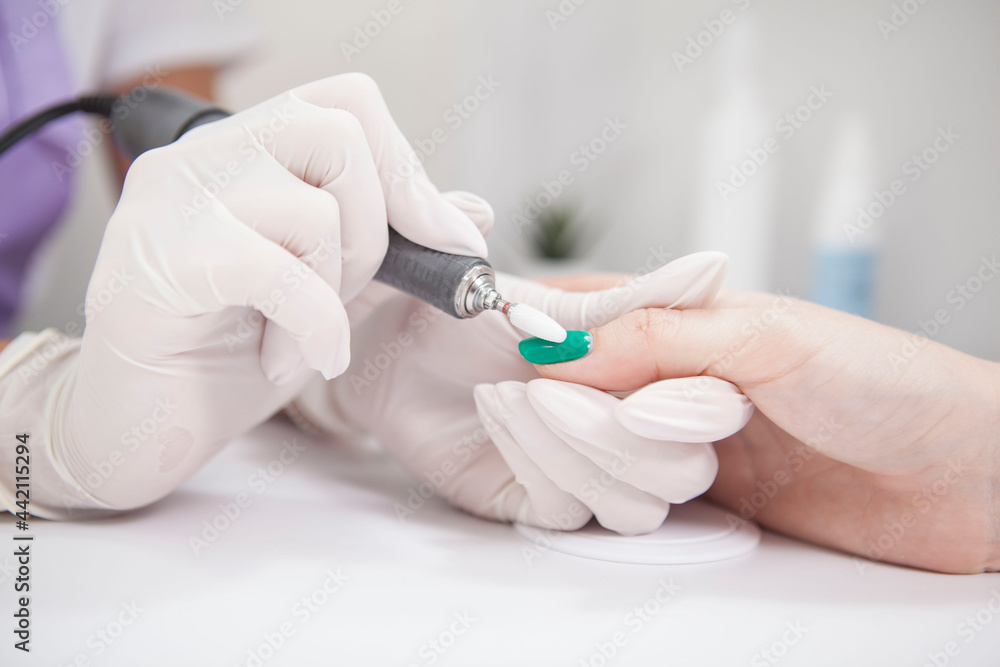 Close up of manicurist removing nail gel with nail file drill Close up of manicurist removing nail gel with nail file drill