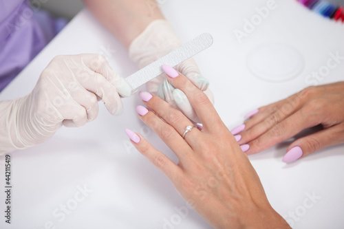 Cropped shot of beautiful female hands during professional manicure by nail technician