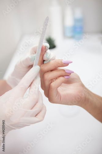 Vertical cropped shot of nail technician doing manicure on female hands